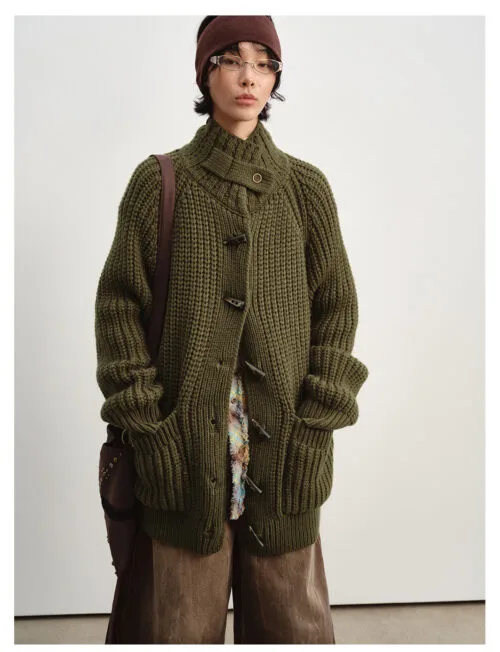 Woman wearing an olive chunky knit cardigan with horn-style toggle buttons