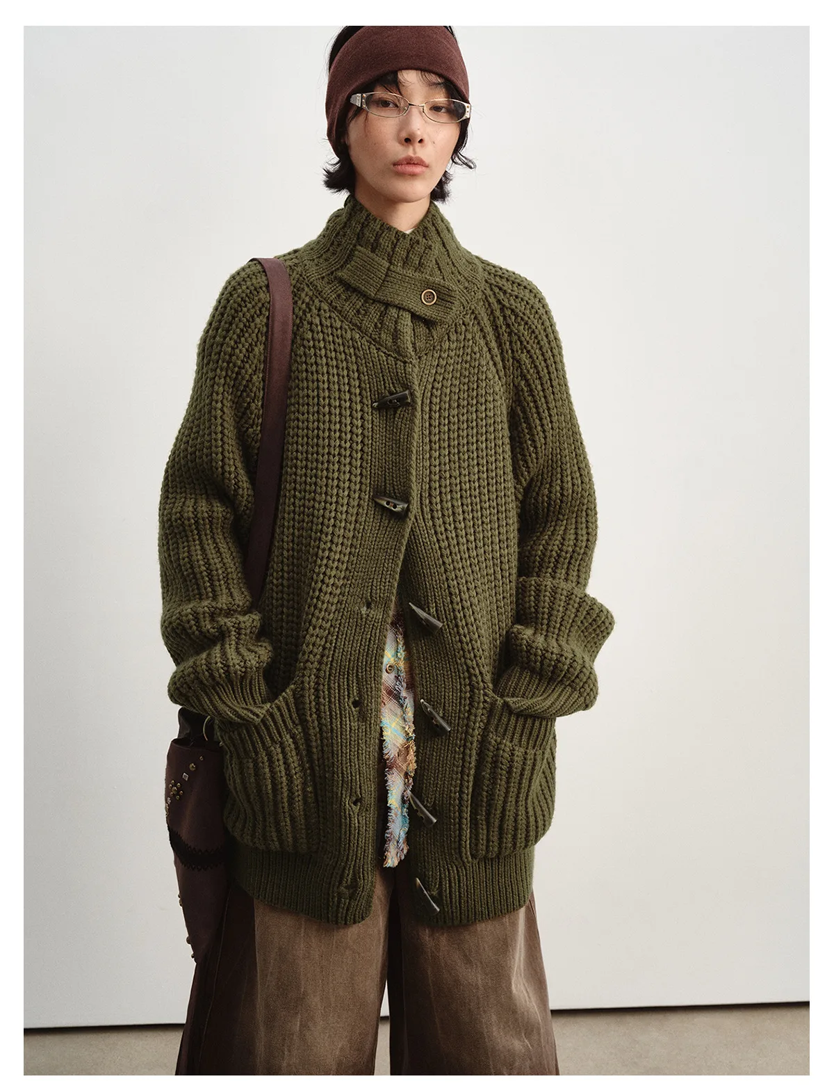 Woman wearing an olive chunky knit cardigan with horn-style toggle buttons