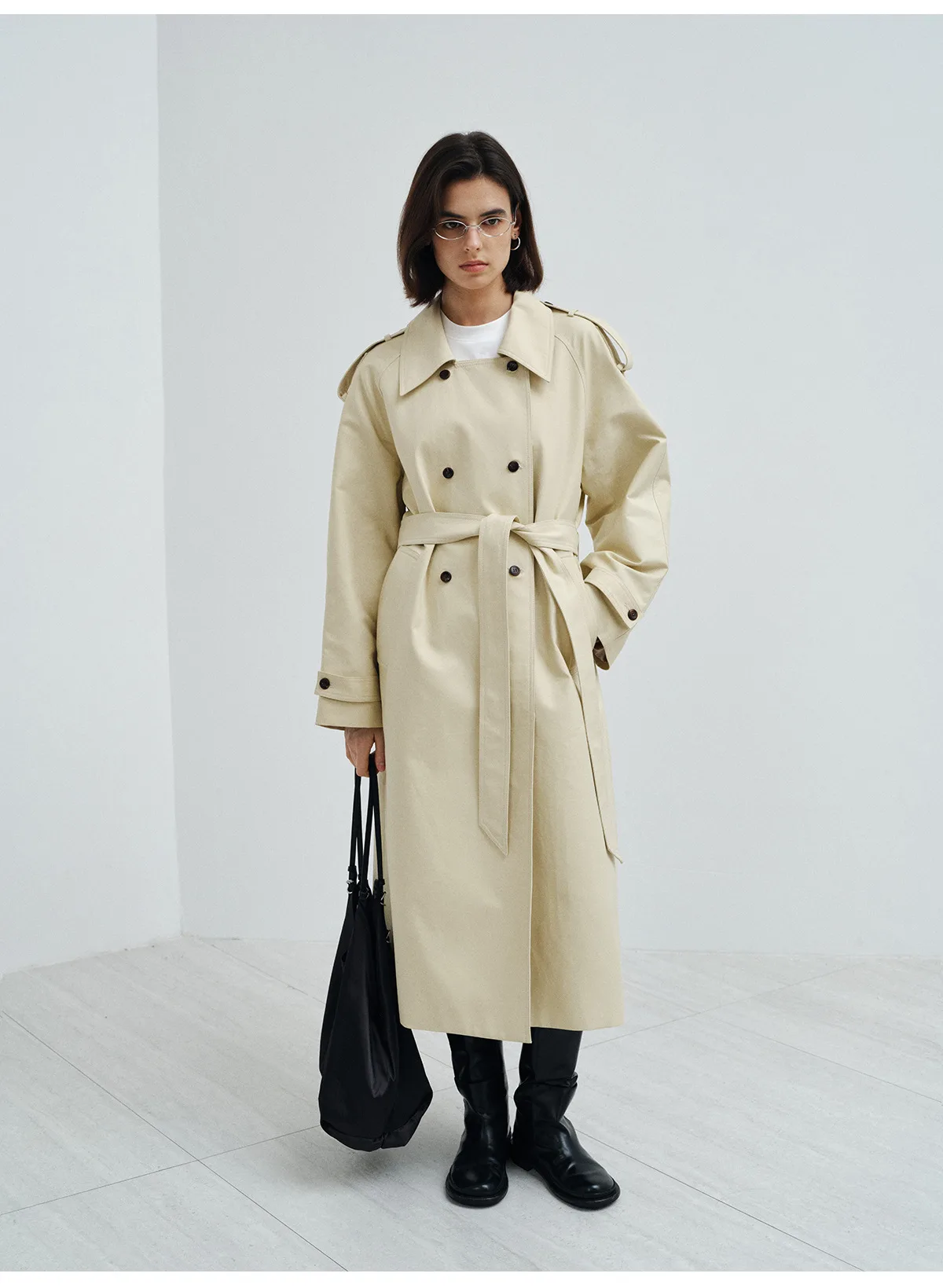Woman wearing a long beige double-breasted cotton trench coat with belt