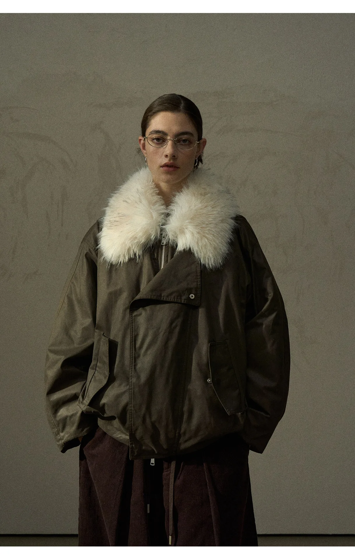 Women wearing a dark olive winter parka with a white faux-fur collar