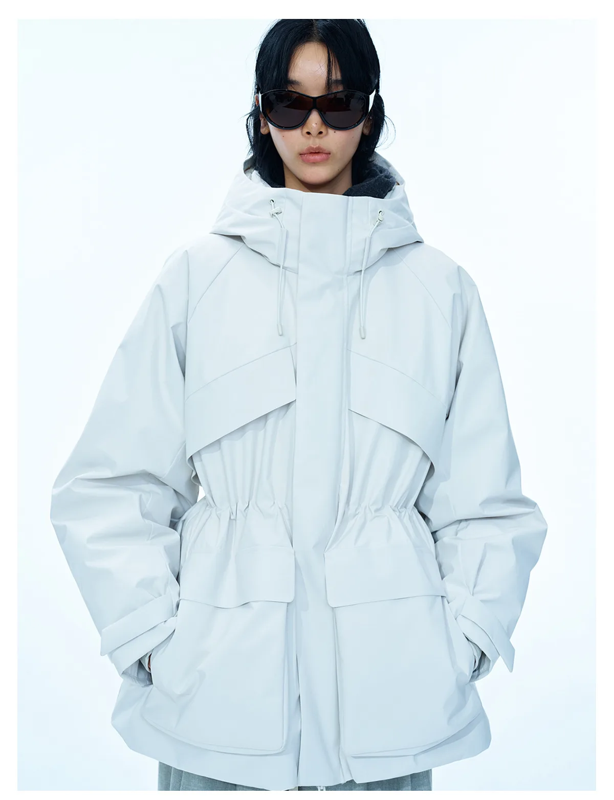 Woman wearing a white hooded down jacket with an adjustable waist