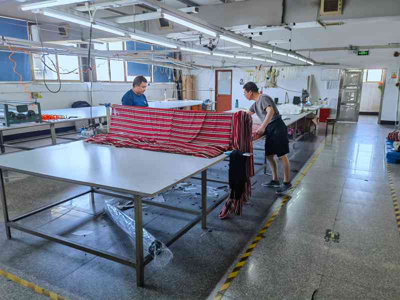 Workers spreading striped fabric on a cutting table during an apparel factory audit